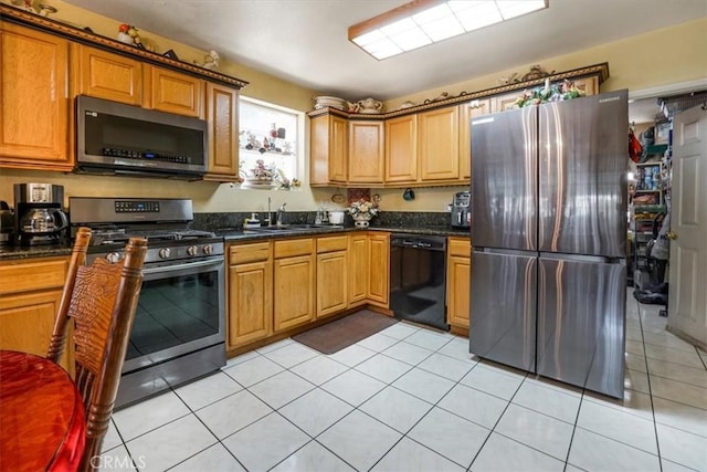 kitchen featuring light tile patterned flooring, sink, stainless steel appliances, and dark stone countertops