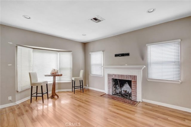 living area with a fireplace, recessed lighting, visible vents, wood finished floors, and baseboards