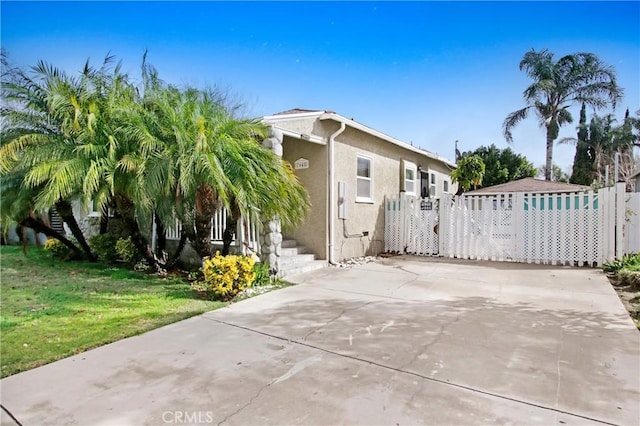 view of front of property featuring a front yard, a gate, and stucco siding