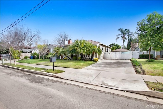 obstructed view of property with a gate, driveway, a front lawn, and fence