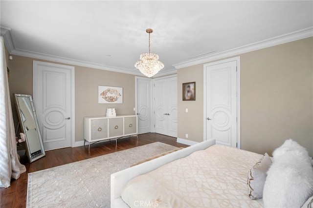 bedroom featuring two closets, dark wood-type flooring, crown molding, and an inviting chandelier