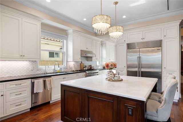 kitchen featuring sink, high quality appliances, a kitchen island, decorative light fixtures, and dark hardwood / wood-style flooring