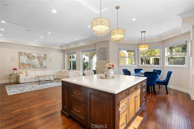 kitchen with crown molding, dark hardwood / wood-style floors, an inviting chandelier, and decorative light fixtures