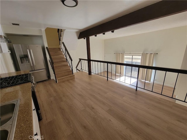 interior space with light hardwood / wood-style flooring, beamed ceiling, and sink