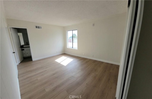 unfurnished bedroom featuring light wood-type flooring and a textured ceiling