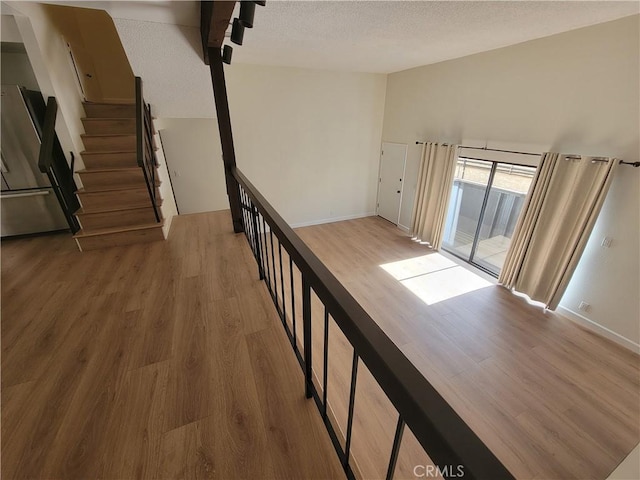 hall featuring light wood-type flooring and a textured ceiling