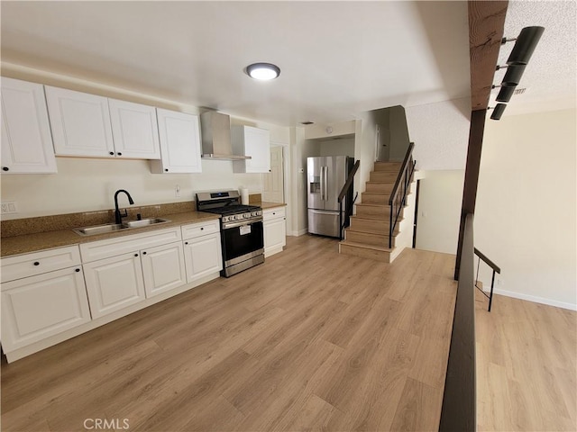 kitchen with light hardwood / wood-style flooring, sink, wall chimney range hood, stainless steel appliances, and white cabinets