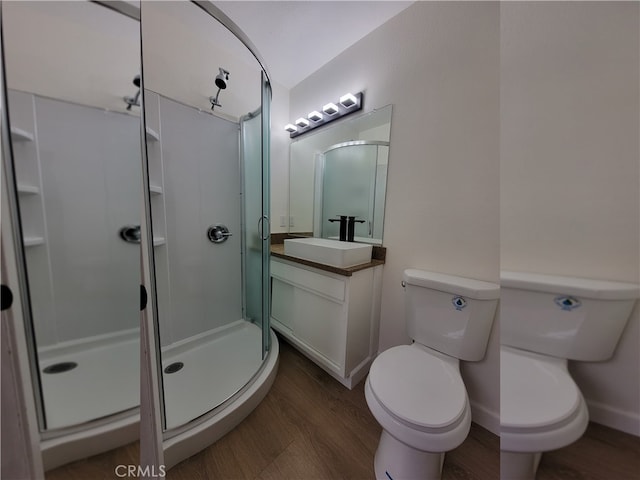 bathroom with toilet, vanity, wood-type flooring, and a shower with shower door