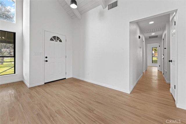 entrance foyer with beam ceiling, high vaulted ceiling, and light hardwood / wood-style floors