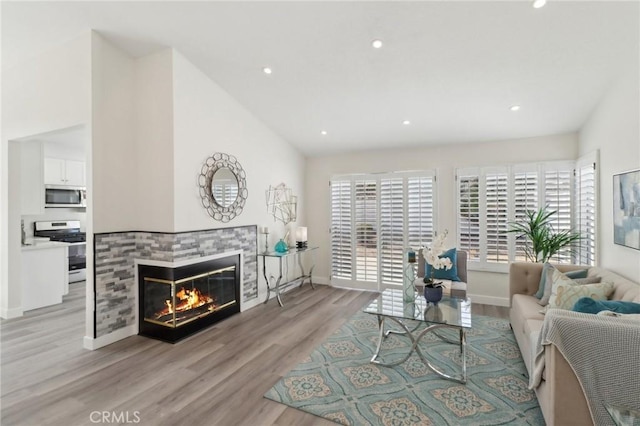 living area featuring baseboards, light wood-type flooring, a tile fireplace, and recessed lighting