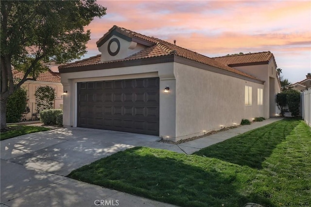 view of front of home featuring stucco siding, concrete driveway, fence, a garage, and a tiled roof