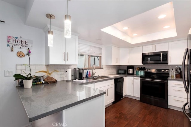 kitchen with white cabinetry, kitchen peninsula, hanging light fixtures, black appliances, and a tray ceiling