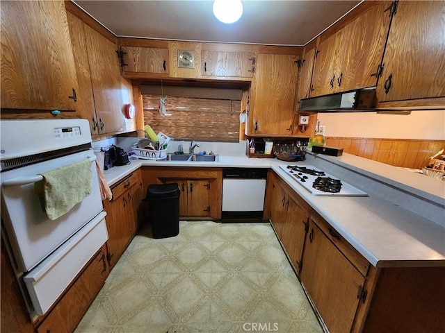 kitchen with white appliances, sink, and range hood