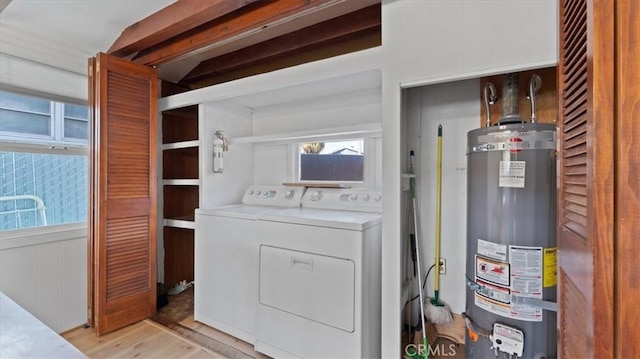 washroom featuring water heater, washing machine and dryer, and light hardwood / wood-style flooring