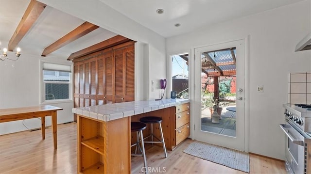 interior space with a wealth of natural light, tile counters, high end stove, and kitchen peninsula