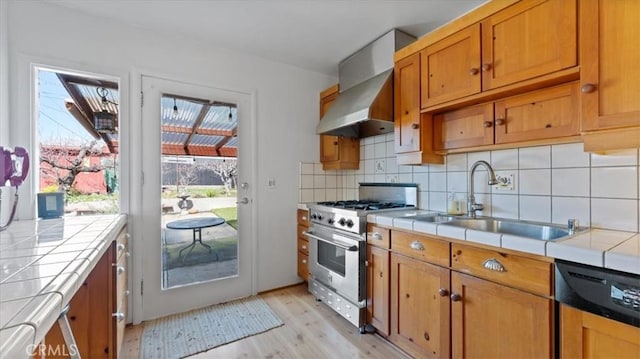 kitchen featuring sink, tile countertops, black dishwasher, and high end range