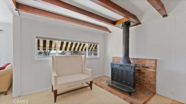 sitting room featuring light carpet, a wood stove, and beam ceiling