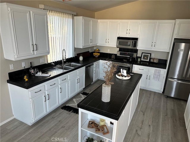 kitchen featuring lofted ceiling, light wood-style flooring, a sink, white cabinets, and appliances with stainless steel finishes