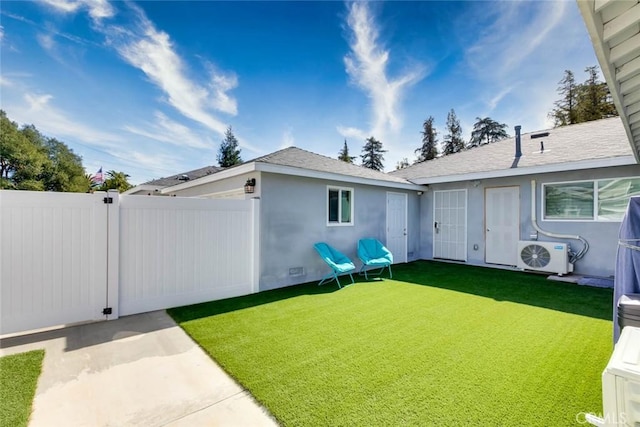 rear view of house with ac unit and a yard