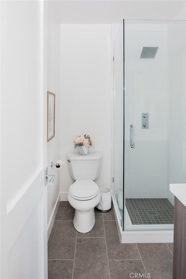 bathroom featuring tile patterned flooring, vanity, toilet, and a shower with shower door