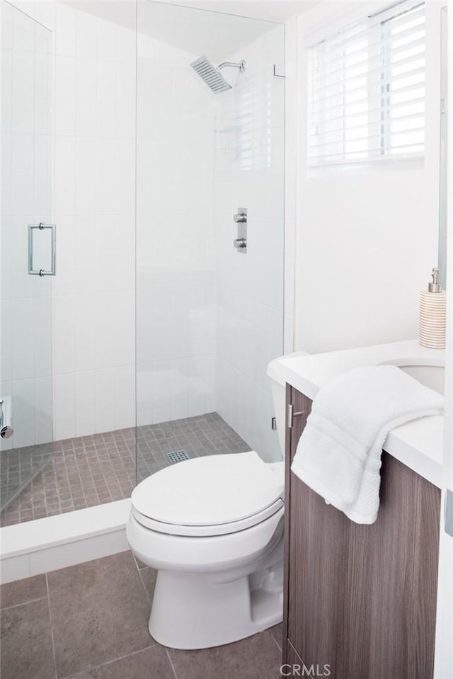 bathroom with vanity, tile patterned flooring, toilet, and walk in shower