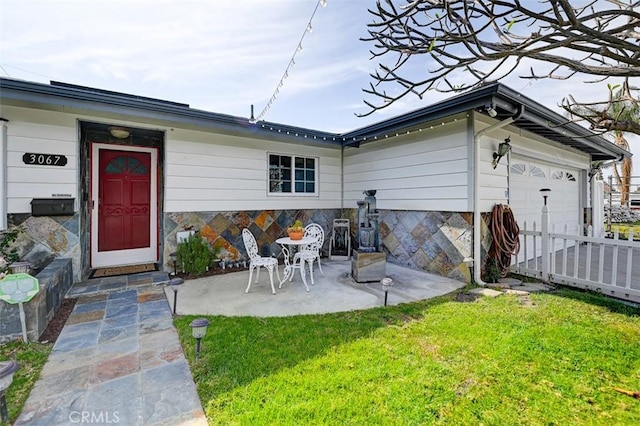 3067 Trinity Dr, Costa Mesa, CA 92626 - back of property featuring stone siding, fence, a yard, and a garage