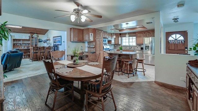 3067 Trinity Dr, Costa Mesa, CA 92626 - dining room featuring a tray ceiling, light wood-style flooring, baseboards, and ceiling fan