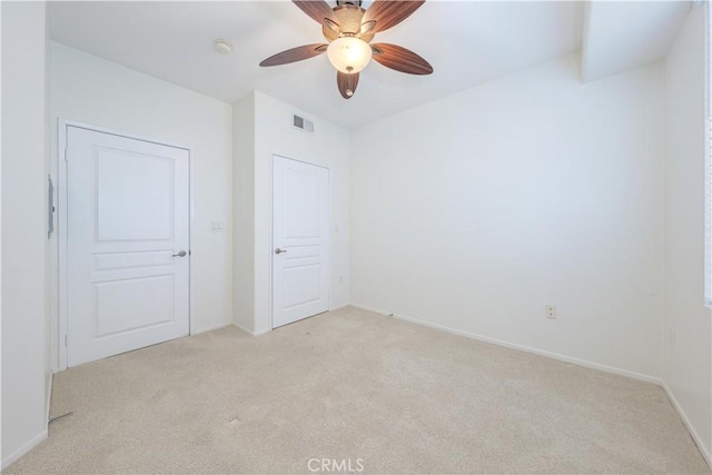 spare room with light carpet, baseboards, visible vents, and a ceiling fan