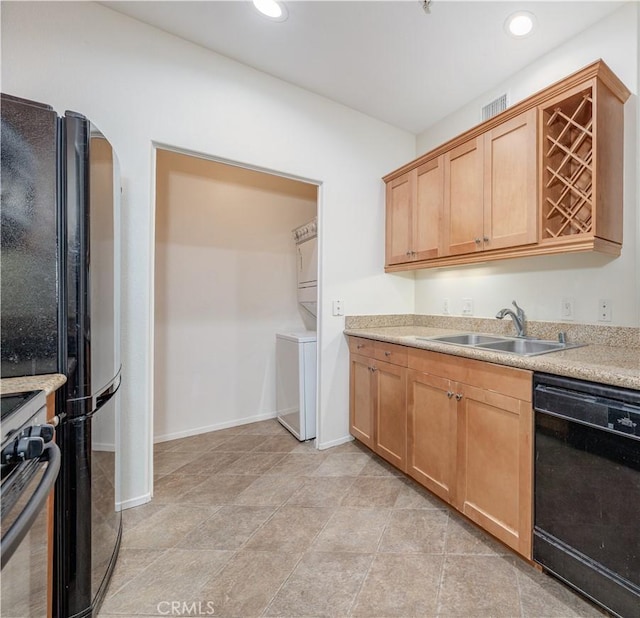 kitchen featuring visible vents, stacked washer and clothes dryer, light countertops, black appliances, and a sink