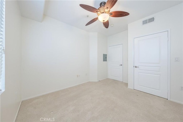 spare room with light carpet, ceiling fan, visible vents, and baseboards