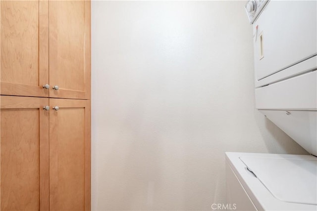 washroom featuring cabinet space and stacked washer and clothes dryer