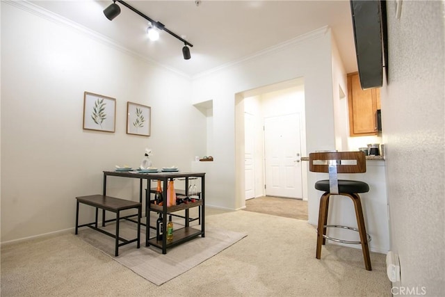 dining area with ornamental molding, baseboards, light carpet, and track lighting