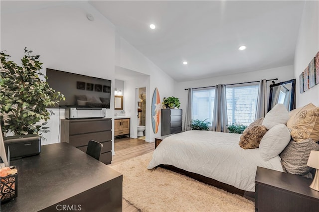 bedroom with high vaulted ceiling, light hardwood / wood-style floors, and ensuite bath