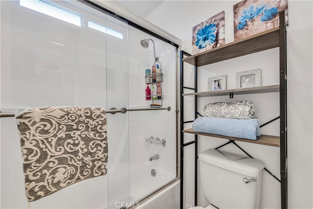 bathroom with bath / shower combo with glass door and toilet