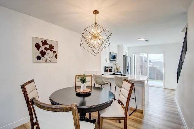 dining area featuring sink, a notable chandelier, and light hardwood / wood-style floors