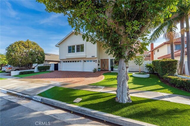 view of front of house with a garage, driveway, a front lawn, and stucco siding