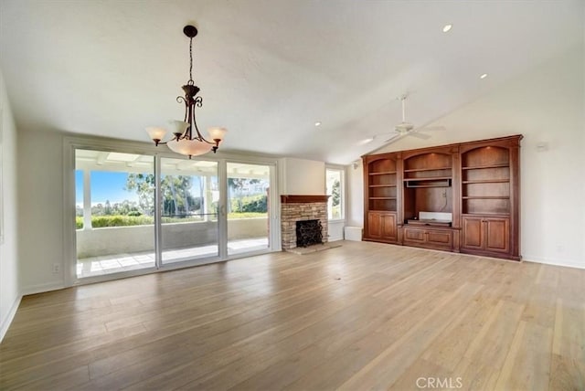 unfurnished living room featuring baseboards, lofted ceiling, light wood-type flooring, a fireplace, and ceiling fan with notable chandelier