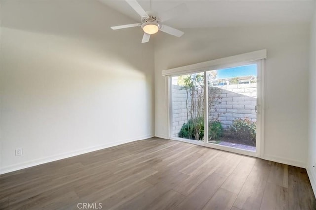 empty room with a ceiling fan, lofted ceiling, baseboards, and wood finished floors