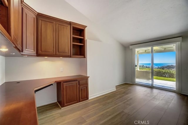 kitchen with light wood-style floors, baseboards, vaulted ceiling, and brown cabinetry