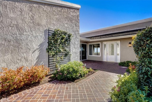 property entrance with a patio area and stucco siding