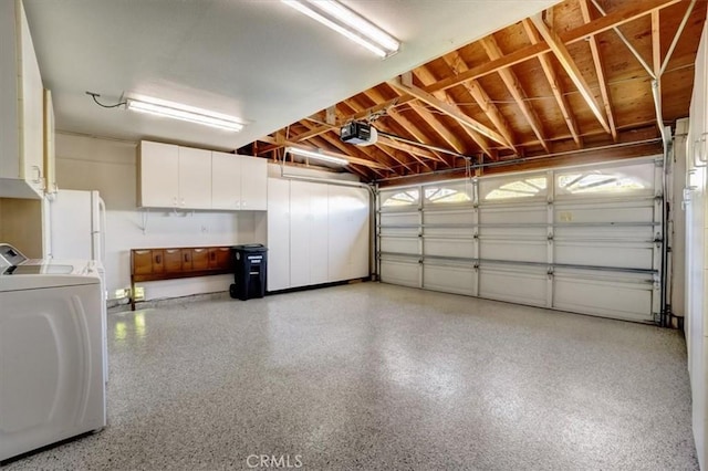 garage with washer and dryer, freestanding refrigerator, and a garage door opener