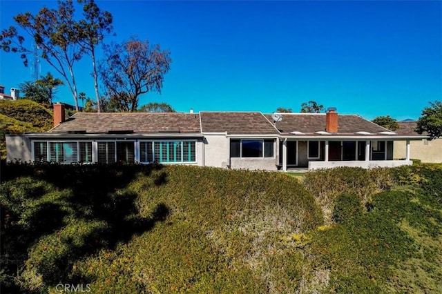 back of property with a chimney and stucco siding