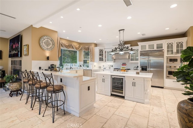 kitchen with a kitchen island, built in appliances, white cabinets, and beverage cooler