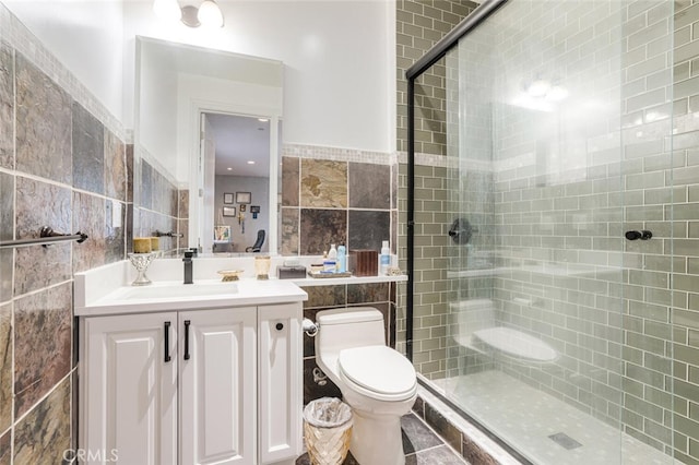 bathroom with toilet, tile walls, vanity, and a shower with door