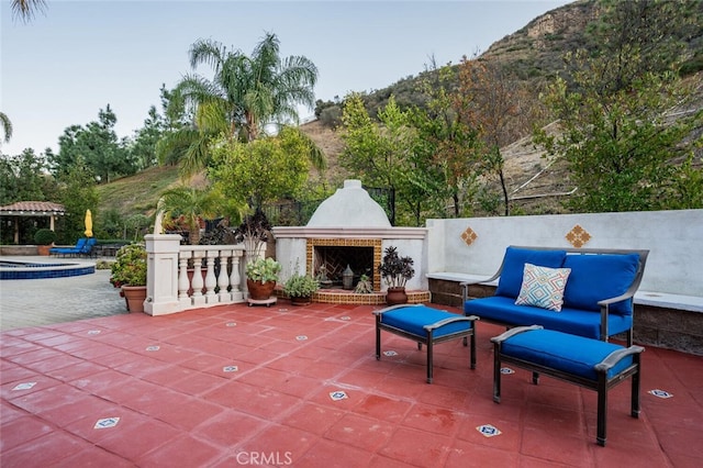 view of patio / terrace featuring an outdoor brick fireplace and a mountain view