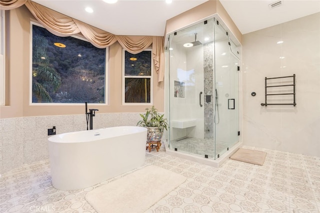 bathroom with tile patterned floors, tile walls, and plus walk in shower