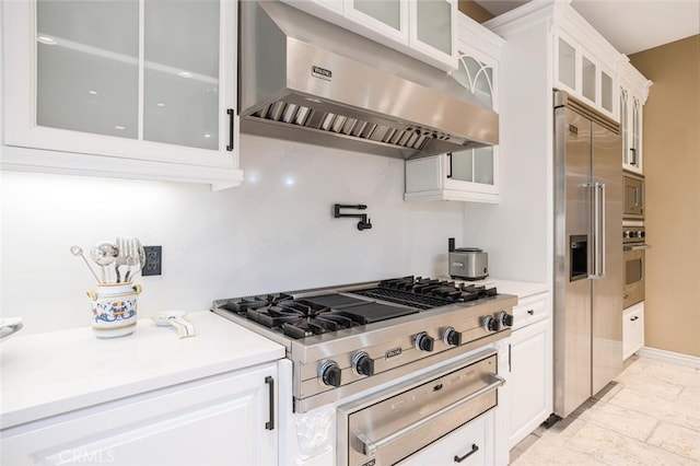 kitchen featuring white cabinets, built in appliances, and range hood