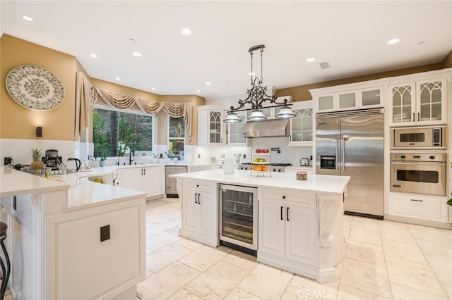 kitchen featuring white cabinetry, built in appliances, beverage cooler, and pendant lighting