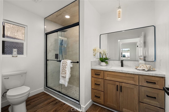 bathroom with vanity, toilet, baseboards, a shower stall, and wood finished floors
