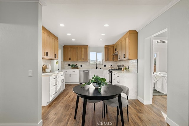 kitchen with tasteful backsplash, ornamental molding, stainless steel appliances, light countertops, and white cabinetry